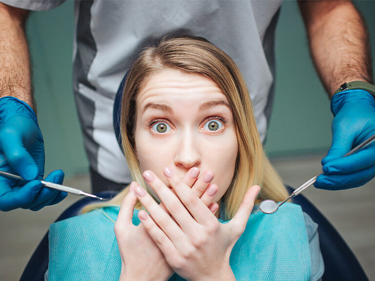 Frau hält sich Hand vor den Mund, Zahnarztangst