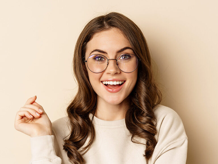 Junge Frau mit Brille lächelt, schöne, gerade Zähne